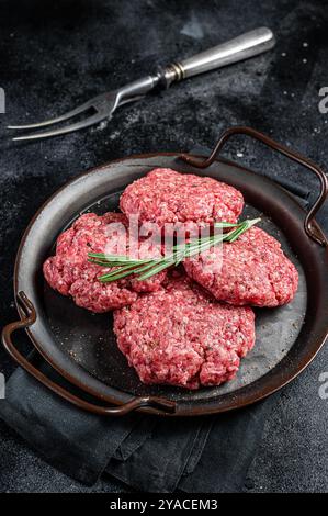 Frikadellen non cuite de viande de bœuf hachée, côtelettes de viande crue. Arrière-plan noir. Vue de dessus. Banque D'Images