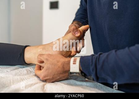 Gros plan sur les mains d'un ostéopathique manipulant la cheville et le pied d'un patient. Traitement médical professionnel en clinique d'ostéopathie, démonstration Banque D'Images