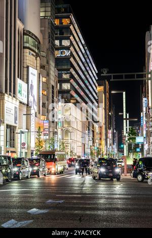 Trafic traversant le célèbre carrefour de Ginza 4 la nuit avec arrière-plan des bâtiments Ginza Core et Ginza six. Entrées de la station de métro. Nuit. Banque D'Images