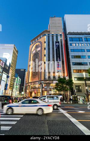 Circulation passant le passage piétonnier devant l'entrée du célèbre magasin Mitsukoshi sur la Ginza à l'heure bleue du soir Banque D'Images