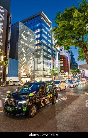 Taxis et voitures alignés devant les magasins phares Bottega Veneta et Giorgio Armani dans la Ginza pendant l'heure bleue du soir. Banque D'Images