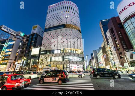 Vue de l'autre côté de la rue sur le showroom de voitures Nissan dans le bâtiment de Ginza place revêtu de blanc sur le Ginza à Tokyo. Voitures passant devant. Banque D'Images