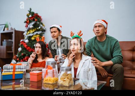 Groupe d'amis profitant de la nuit du film de Noël avec des collations et un décor festif Banque D'Images