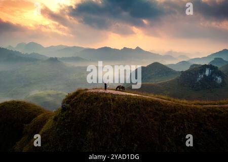 Vue aérienne du beau lever de soleil sur la colline d'herbe de Ba Guang, chaîne de montagnes et brouillard avec le villageois apportant leur cheval pour paître sur la montagne Banque D'Images