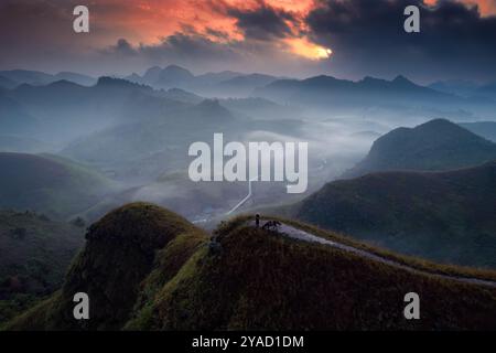 Vue aérienne du beau lever de soleil sur la colline d'herbe de Ba Guang, chaîne de montagnes et brouillard avec le villageois apportant leur cheval pour paître sur la montagne Banque D'Images