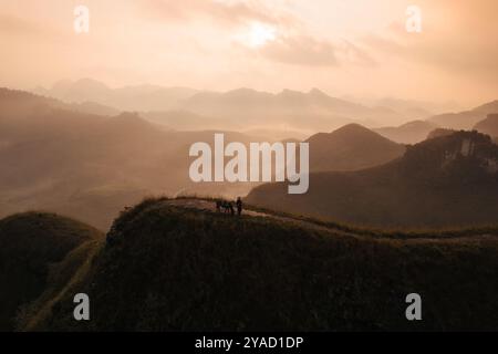 Vue aérienne du beau lever de soleil sur la colline d'herbe de Ba Guang, chaîne de montagnes et brouillard avec le villageois apportant leur cheval pour paître sur la montagne Banque D'Images