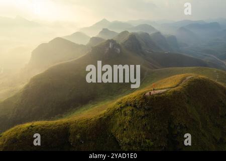 Vue aérienne de la belle colline d'herbe de Ba Guang, chaîne de montagnes avec brouillard et villageois apportant cheval à paître sur la montagne dans la matinée à Ha Lang, Banque D'Images