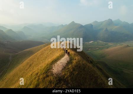 Vue aérienne de la belle colline d'herbe de Ba Guang, chaîne de montagnes avec brouillard et villageois apportant cheval à paître sur la montagne dans la matinée à Ha Lang, Banque D'Images