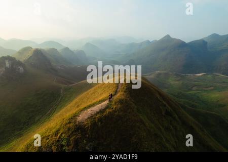 Vue aérienne de la belle colline d'herbe de Ba Guang, chaîne de montagnes avec brouillard et villageois apportant cheval à paître sur la montagne dans la matinée à Ha Lang, Banque D'Images