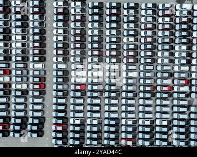 Vue aérienne du parking de l'usine de montage de véhicules emballé avec des voitures, camionnettes et VUS. Logistique, stratégie de transport, électrique et hybride Banque D'Images