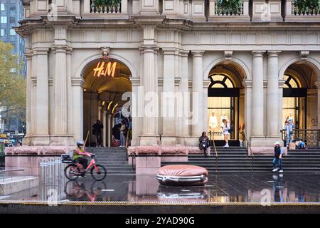 Les gens dans le Bourke Street Mall devant le magasin H&M dans l'ancien bâtiment GPO par un après-midi de pluie dans le quartier des affaires de Melbourne, Victoria, Australie. Banque D'Images