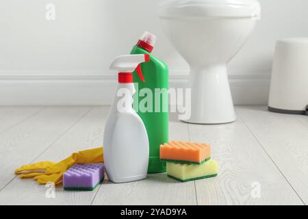 Nettoyants pour toilettes, éponges et gants sur le sol dans la salle de bains Banque D'Images