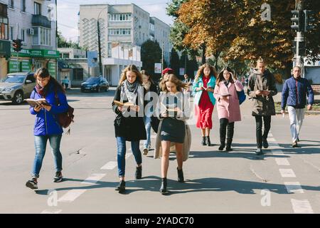 Romny, Ukraine, 29 septembre 2019 : de jeunes femmes et hommes marchent sur le passage et regardent un livre ouvert. Banque D'Images