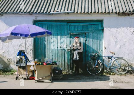 Romny, Ukraine, 29 septembre 2019 : une jeune femme se tient près d'une vieille maison et lit un livre. Banque D'Images