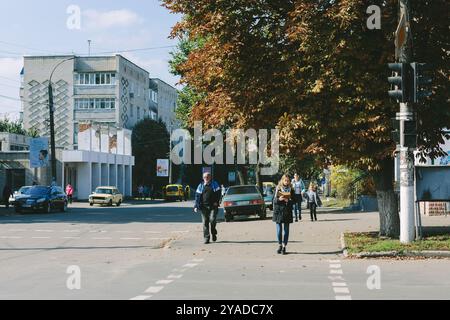 Romny, Ukraine, le 29 septembre 2019 : une jeune femme se tient près d'un passage pour piétons et regarde un livre ouvert. Banque D'Images