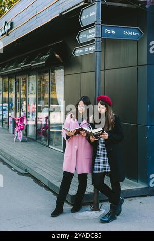 Romny, Ukraine, 29 septembre 2019 : deux jeunes femmes se tiennent dans la rue et lisent un livre. Banque D'Images