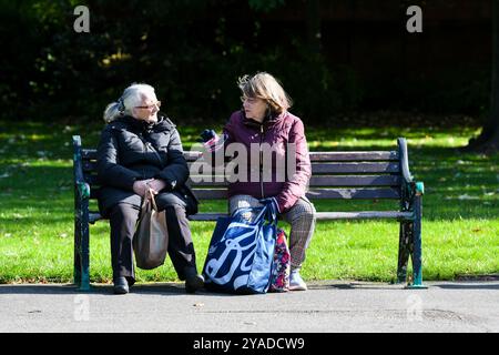 deux retraités assis sur un banc de parc parlant Banque D'Images