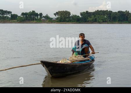 Rivière Gorai-Madhumati au Bangladesh. Soir au bord de la rivière. Les pêcheurs pêchent dans des bateaux au milieu de la rivière. La rivière coule sous le twilig Banque D'Images