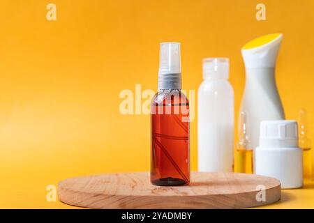 Un vaporisateur brun se tient sur une surface en bois avec un fond jaune vif. D'autres bouteilles en blanc et jaune sont floues dans le fond, CREA Banque D'Images