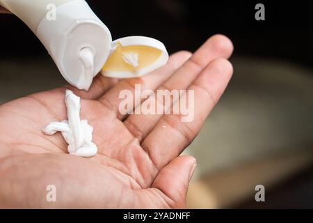 Une personne pressant la lotion d'un tube sur sa main. Banque D'Images