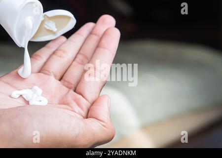 Une personne pressant la lotion d'un tube sur sa main. Banque D'Images