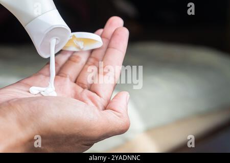 Une personne pressant la lotion d'un tube sur sa main. Banque D'Images