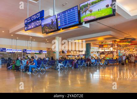 Aire d'attente très fréquentée de l'aéroport international avec des voyageurs assis près des portes d'embarquement. Mexique. Cancun. Banque D'Images