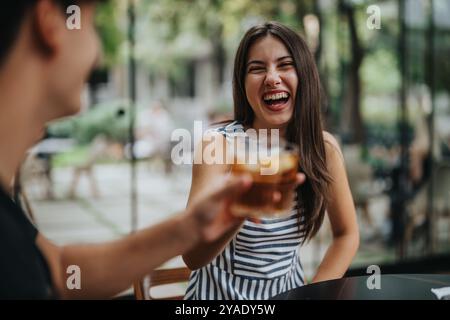 Amis joyeux riant et grillant dans un cadre de café en plein air Banque D'Images