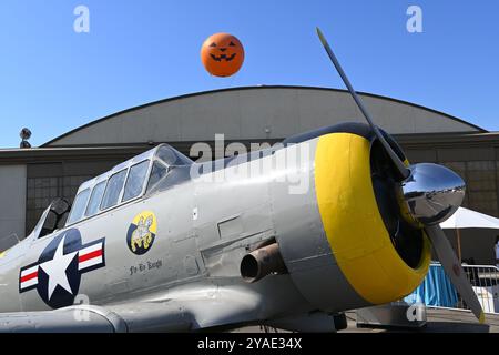 IRVINE, CALIFORNIE - 05 OCT 2024 : Antique Airplane au Great Park avec le tour en montgolfière avec le visage de citrouille s'élevant au-dessus du hangar. Banque D'Images