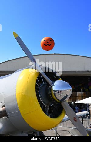 IRVINE, CALIFORNIE - 05 OCT 2024 : Antique Airplane au Great Park avec le tour en montgolfière avec le visage de citrouille s'élevant au-dessus du hangar. Banque D'Images