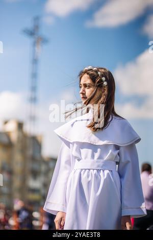 Lida, Biélorussie - 15 juin 2021 : jeune fille portant une robe blanche et une couronne de fleurs debout près de l'église le premier jour de communion Banque D'Images