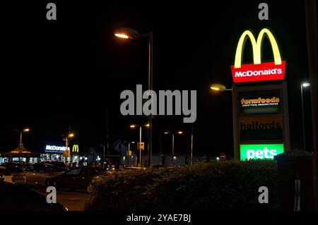 Affiche lumineuse avec un plat McDonald's à emporter en arrière-plan la nuit Banque D'Images