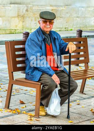 Homme âgé avec canne assis sur une banquette en bois - Loches, Indre-et-Loire (37), France. Banque D'Images
