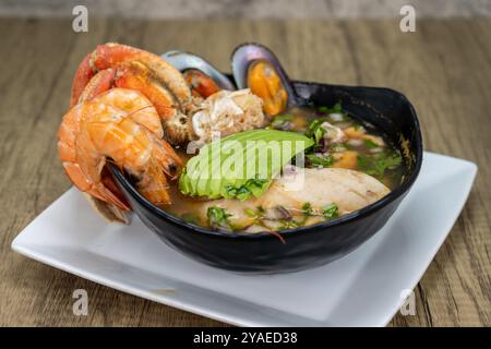 Soupe de crustacés de fruits de mer avec crevettes, crabe, avocat, poisson blanc et moules servie chaude dans un bol. Banque D'Images