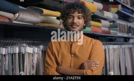 Heureux client acheteur d'homme indien arabe souriant dans l'atelier de magasin de tissu avec des échantillons de tissus de tissus de tissus de laine de soie de fibres textiles de mode Banque D'Images