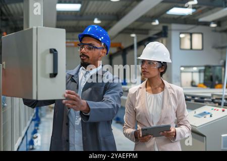Gestionnaire indienne et ingénieur en chef afro-américain marchant à travers l'usine, parlant et planifiant l'optimisation de la production, vue de face. Banque D'Images