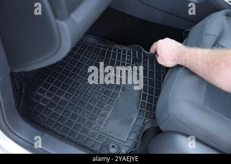 Homme prenant tapis de voiture en caoutchouc noir de l'auto, gros plan Banque D'Images