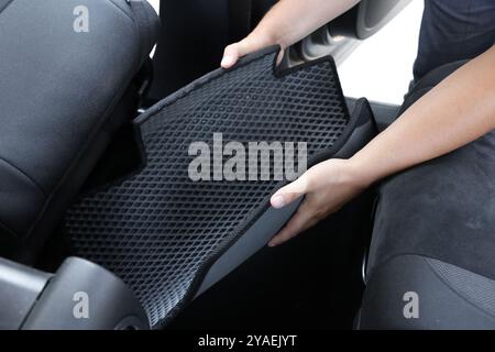 Homme prenant tapis de voiture en caoutchouc gris de l'auto, gros plan Banque D'Images