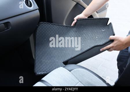 Homme prenant tapis de voiture en caoutchouc gris de l'auto, gros plan Banque D'Images