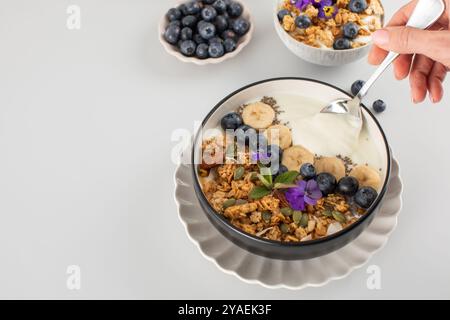 Une femme prend un yaourt naturel avec une cuillère à granola. Petit déjeuner. Copier l'espace Banque D'Images