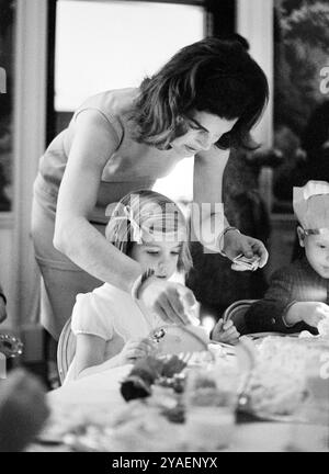 La première dame des États-Unis Jacqueline Kennedy allumant une bougie d’anniversaire pour sa fille, Caroline Kennedy, lors d’une fête conjointe pour Caroline et John F. Kennedy, Jr., salle à manger du président, Maison Blanche, Washington, DC, USA, Cecil Stoughton, White House Photographs, 14 novembre, 1962 Banque D'Images