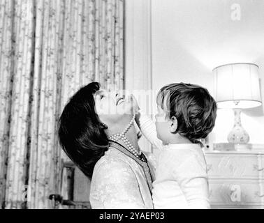 La première dame des États-Unis Jacqueline Kennedy riant alors que son fils, John F. Kennedy, Jr., joue avec son collier de perles simulées dans la pépinière de John, Maison Blanche, Washington, DC, États-Unis, Cecil Stoughton, photographies de la Maison Blanche, 27 novembre 1962 Banque D'Images