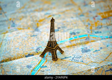 Une réplique miniature en métal de la Tour Eiffel se dresse sur un plan de rue de Paris en papier pour illustration et divertissement Banque D'Images