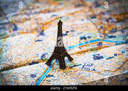 Une réplique miniature en métal de la Tour Eiffel plane sur un plan de rue de Paris en papier pour illustration et utilisation conceptuelle Banque D'Images