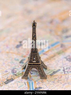 Une réplique miniature en métal de la Tour Eiffel se dresse sur un plan de rue de Paris en papier pour illustration et divertissement Banque D'Images