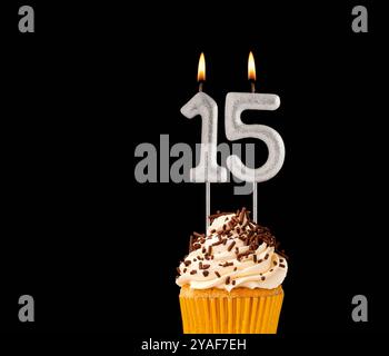 Cupcake d'anniversaire sur fond noir - bougies en forme de numéro 15. Banque D'Images