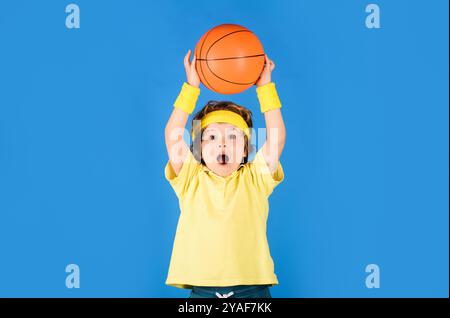 Petit basket-ball en vêtements de sport lancer une balle de basket-ball. Jeu de sport. Fitness, entraînement et mode de vie actif des enfants. Joueur de basket-ball dans le sport unifo Banque D'Images