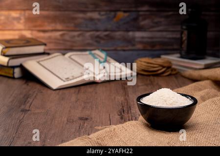 Saint Coran et un grain de riz dans un bol en bois dans le sac sur une table en bois, concept de zakat islamique. Musulmans pour aider les pauvres et les nécessiteux. Conceptuel s Banque D'Images