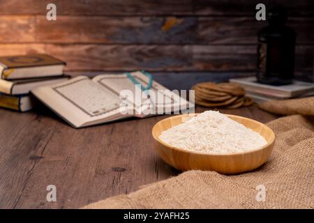 Saint Coran et un grain de riz dans un bol en bois dans le sac sur une table en bois, concept de zakat islamique. Musulmans pour aider les pauvres et les nécessiteux. Conceptuel s Banque D'Images