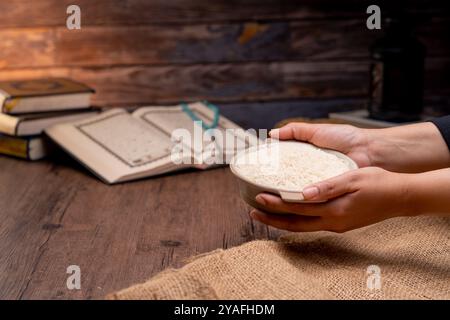 Saint Coran et un grain de riz dans un bol en bois dans le sac sur une table en bois, concept de zakat islamique. Musulmans pour aider les pauvres et les nécessiteux. Conceptuel s Banque D'Images